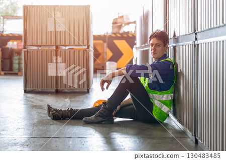 warehouse worker wear reflective vest sitting on the ground floor relax brake rest from tired work 130483485