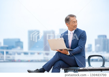 Senior man using a laptop outdoors 130483700