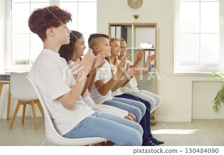 Group of happy children applauding after presentation in class or at school event Group of happy children applauding after presentation in class or at school event 130484090