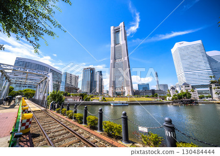 A rare sight in the Yokohama cityscape of Japan: exposed rails...View of Yokohama Landmark Tower and the bustling Nippon Maru from the railway road... 130484444