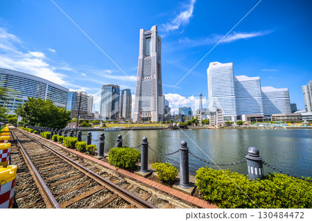 A rare sight in the Yokohama cityscape of Japan: exposed rails...View of Yokohama Landmark Tower and the bustling Nippon Maru from the railway road... 130484472
