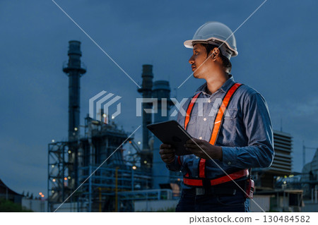 Night shift engineer oil and gas refinery service, male worker hard work in petroleum industry plant dark background. Night shift engineer oil and gas refinery service, male worker hard work in petroleum industry plant dark background. 130484582