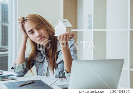 Young people looking at home model feeling anxious worry stress thinking about house bill loan debt 130484595