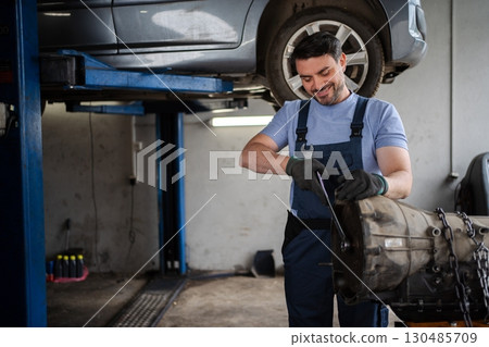 Mechanic repairing a car gearbox in a workshop Mechanic repairing a car gearbox in a workshop 130485709