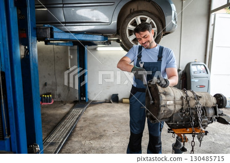 Mechanic working on a gearbox in a car repair shop Mechanic working on a gearbox in a car repair shop 130485715