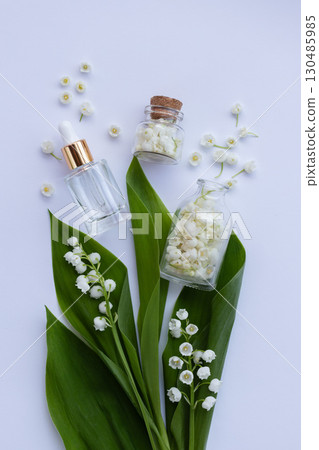 Glass bottle of lily of the valley essential oil with fresh flowers. Copy space. 130485985