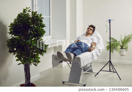 Male patient lying in hospital bed with iv drip attached to his hand Male patient lying in hospital bed with iv drip attached to his hand 130486605