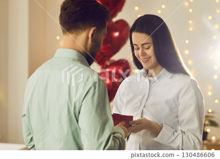 Man holding red present box in his hand and congratulating pretty woman on holiday. 130486606