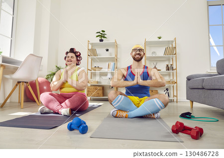 Funny couple doing yoga together in living room at home 130486728