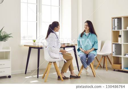Smiling happy pregnant woman visiting her obstetrician doctor in maternity clinic. 130486764