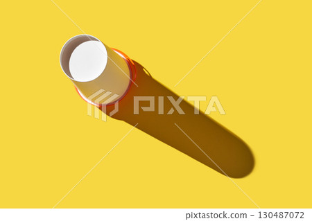 Minimalist white paper cup with long shadow on bright yellow background 130487072