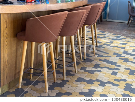 Bar counter with stools and hexagonal floor tiles. Hospitality, leisure, and social culture in modern interior spaces. 130488016