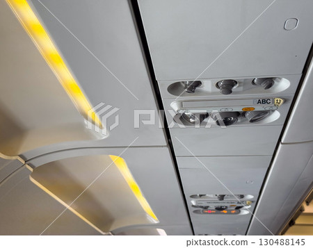 Closeup of airplane cabin panel with air vents and light controls. Passenger service and aviation engineering. 130488145