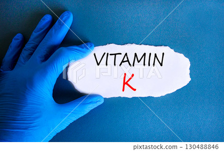 Vitamin K phylloquinone symbol. Concept words Vitamin K on beautiful white paper. Doctor's hand blue medical glove. Beautiful blue background. Medical healthy lifestyle Vitamin K phylloquinone concept 130488846