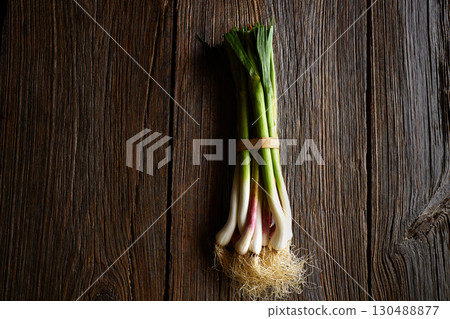 Green garlic bunch on a wooden background Green garlic bunch on a wooden background 130488877
