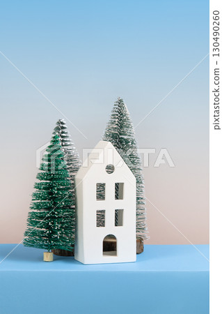 Christmas winter card with green trees and a white house on a blue and gray gradient background with space for text, greetings, promotions, and discounts. 130490260