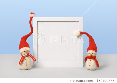 Christmas background with knitted snowmen in red hats with white frame and space for text, greetings, promotions, and discounts. Christmas and New Year card. 130490277
