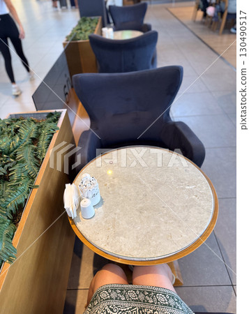 Small round table with condiments and napkins in airport cafe. Waiting, hospitality, and lifestyle moments of travelers in transit spaces. Small round table with condiments and napkins in airport cafe. Waiting, hospitality, and lifestyle moments of travelers in transit spaces. 130490517