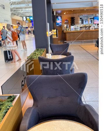 Comfortable lounge chairs and tables in airport cafe area. Leisure, travel and social interaction in public hospitality spaces. 130490518