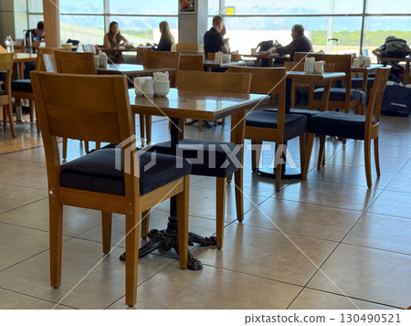 Wooden tables and chairs in a bright cafe interior. Socialization, leisure and human connection in everyday hospitality spaces. 130490521