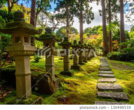 A Japanese garden in the daytime, with stone lanterns lined up in a straight line and a stone-paved path 130490539