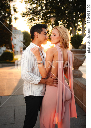 Couple embracing warmly during sunset stroll in a vibrant city Couple embracing warmly during sunset stroll in a vibrant city 130491402