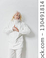 elderly man wearing a stylish white jacket standing against a plain white background, showcasing modern fashion and confidence with a subtle expressive gesture 130491814