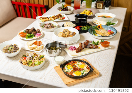 Traditional Middle Eastern dishes served on a white table in restaurant interior Traditional Middle Eastern dishes served on a white table in restaurant interior 130491892