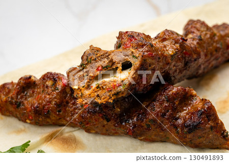 Close-up of grilled kebab with melted cheese inside on flatbread, juicy and spicy 130491893