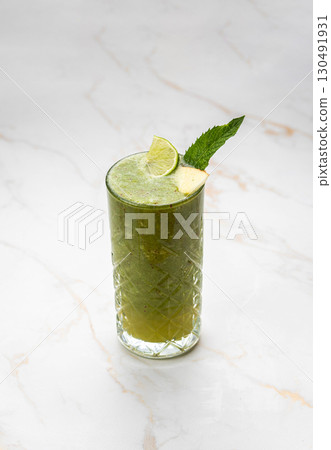 Green detox smoothie with lime and mint in a glass on marble background Green detox smoothie with lime and mint in a glass on marble background 130491931