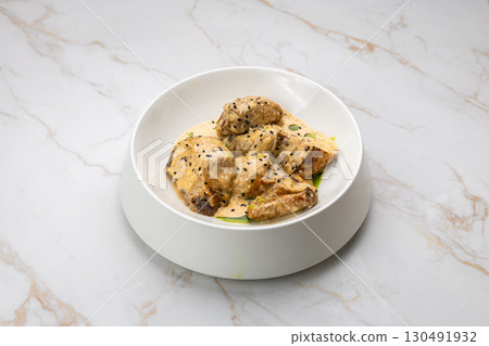 Chicken in creamy mustard sauce with black sesame, served on white marble background Chicken in creamy mustard sauce with black sesame, served on white marble background 130491932
