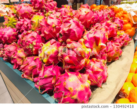 Fresh dragon fruits stacked on display at a market. Vibrant pink skin with green scales, tropical exotic fruit rich in nutrients, perfect for juice, smoothies, or desserts. Fresh dragon fruits stacked on display at a market. Vibrant pink skin with green scales, tropical exotic fruit rich in nutrients, perfect for juice, smoothies, or desserts. 130492418