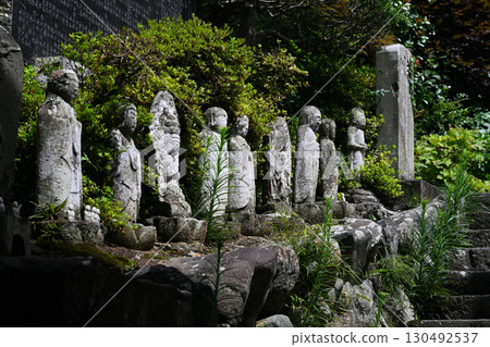 A row of old moss-covered stone Buddha statues 130492537