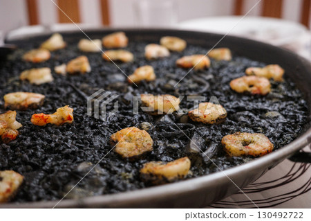 Traditional Spanish black rice paella with prawns served in a pan 130492722