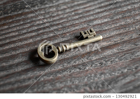 Antique key with intricate designs lying on wooden surface 130492921