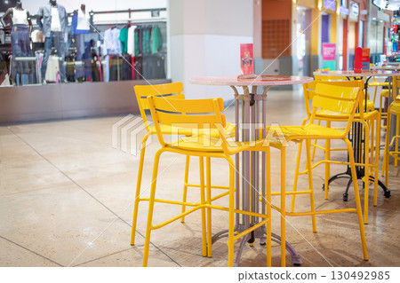 購物中心裡的咖啡館。黃色的椅子和桌子 購物中心裡的咖啡館。黃色的椅子和桌子 130492985