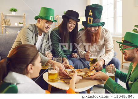 Happy friends celebrating Saint Patrick's Day eating pizza and drinking beer at home. 130493045