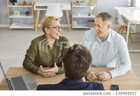 Happy senior couple visiting realtor, agent, discussing insurance agreement, real estate contract Happy senior couple visiting realtor, agent, discussing insurance agreement, real estate contract 130493057