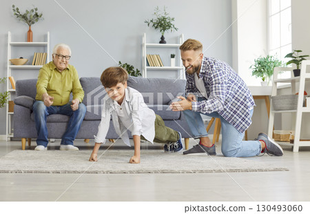 Child doing push-ups sport exercises at home with father and grandfather supporting him 130493060