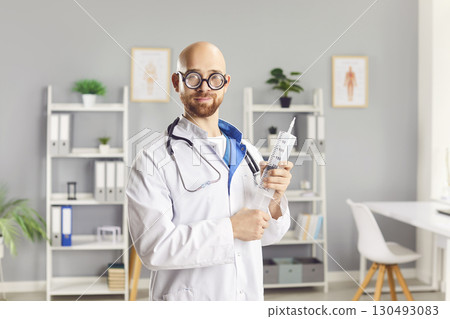 Funny Doctor Holding A Large Syringe In Clinic Funny Doctor Holding A Large Syringe In Clinic 130493083