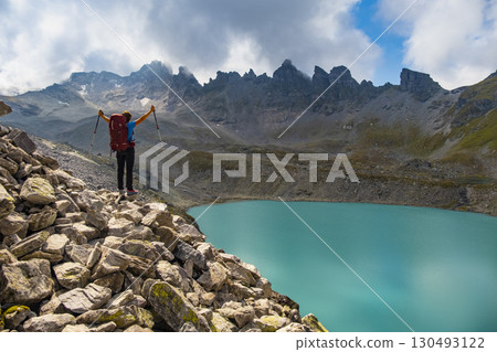 Female hiker with backpack enjoying epic view of Wildsee lake on Pizol mountain range in Switzerland. Travel sport wanderlust concept. 130493122