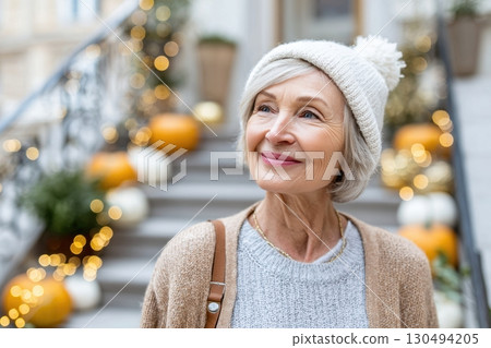 Elderly woman with curly gray hair sits by a cafe window, holding a warm drink and smiling softly as she gazes outside, enjoying a peaceful moment. 130494205