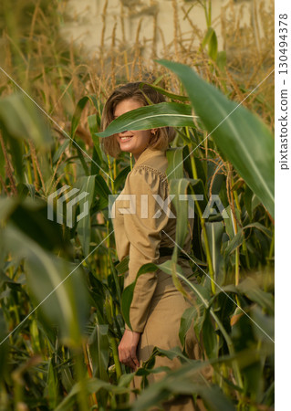 Beautiful model girl posing at camera on morning sunrise over the corn field. Funny joyful woman with cute smile 130494378