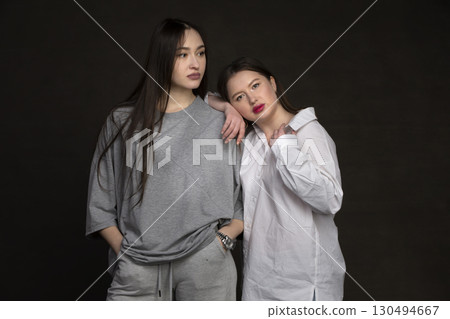 Two beautiful girls-friends on a dark background. Two beautiful girls-friends on a dark background. 130494667