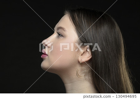 Profile of a young female model with perfect sensual lips and closed eyes on a black background. Beautiful facial skin, augmentation of female lips, glamorous elegance. 130494695