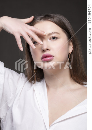 Beautiful girl model with sensual full lips with natural makeup on a gray background. Beautiful girl model with sensual full lips with natural makeup on a gray background. 130494704