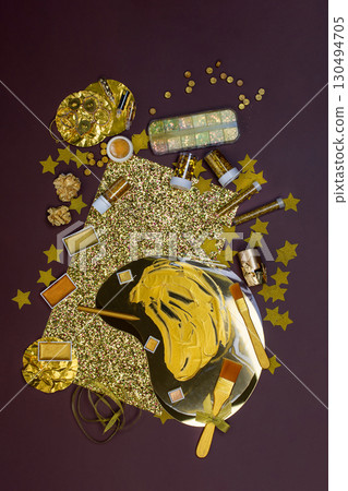 Composition with gold accessories on table. Applying gold paint and gold foil to a work of art Composition with gold accessories on table. Applying gold paint and gold foil to a work of art 130494705