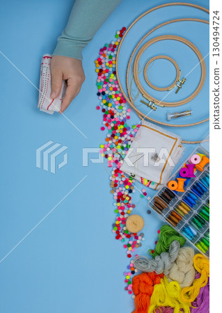 Woman working with embroidery. Very nice young woman embroiders with special embroidery threads. 130494724