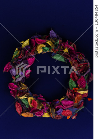 A wreath of dried multi-colored petals on a dark background. A wreath of dried multi-colored petals on a dark background. 130494854
