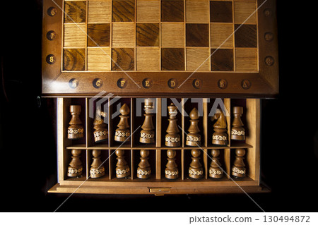 Dark chess pieces lie in a box. A puzzle game with tricky combinations that requires planning and thinking. 130494872